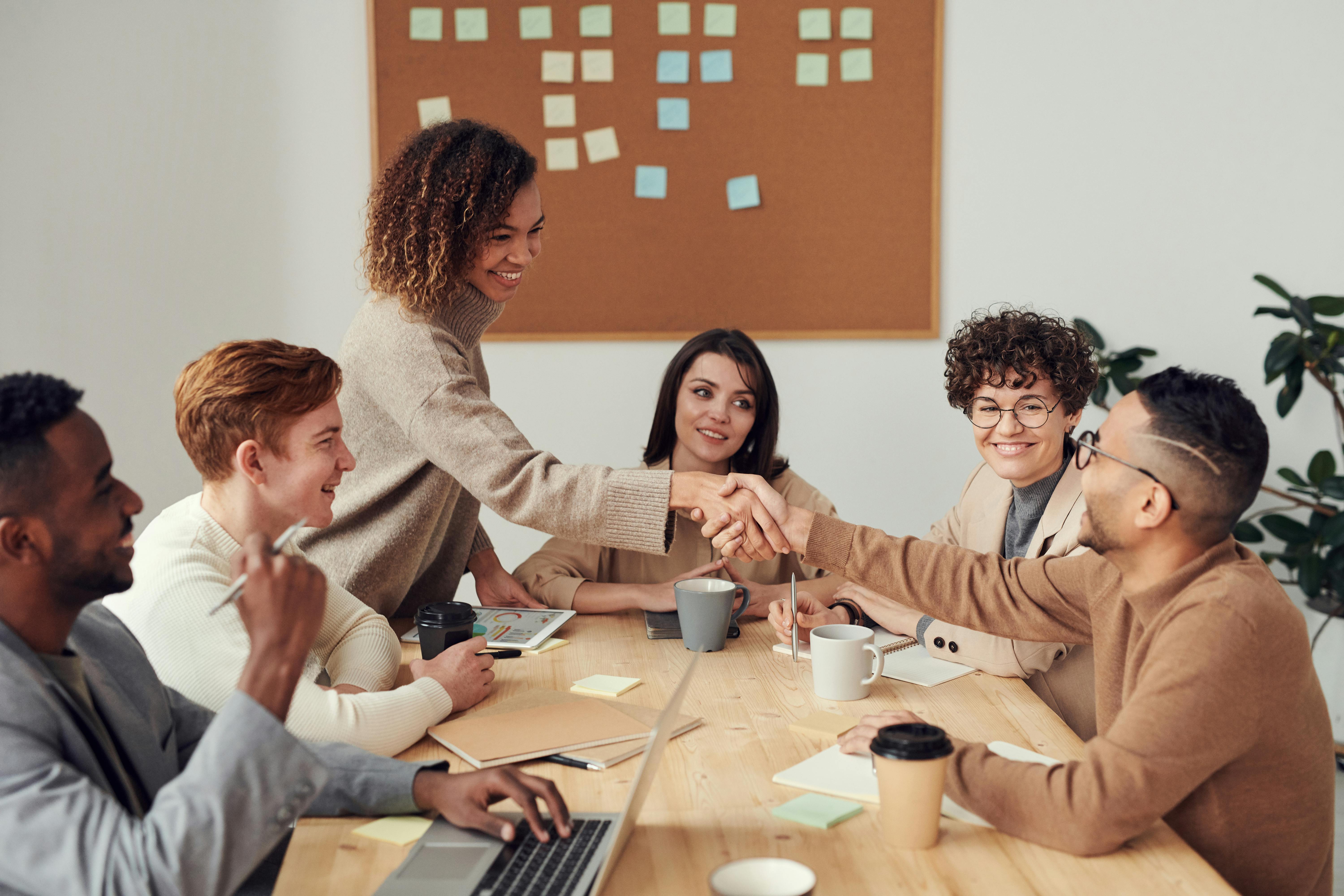 A team in a strategy meeting collaborating around laptops and a conference table