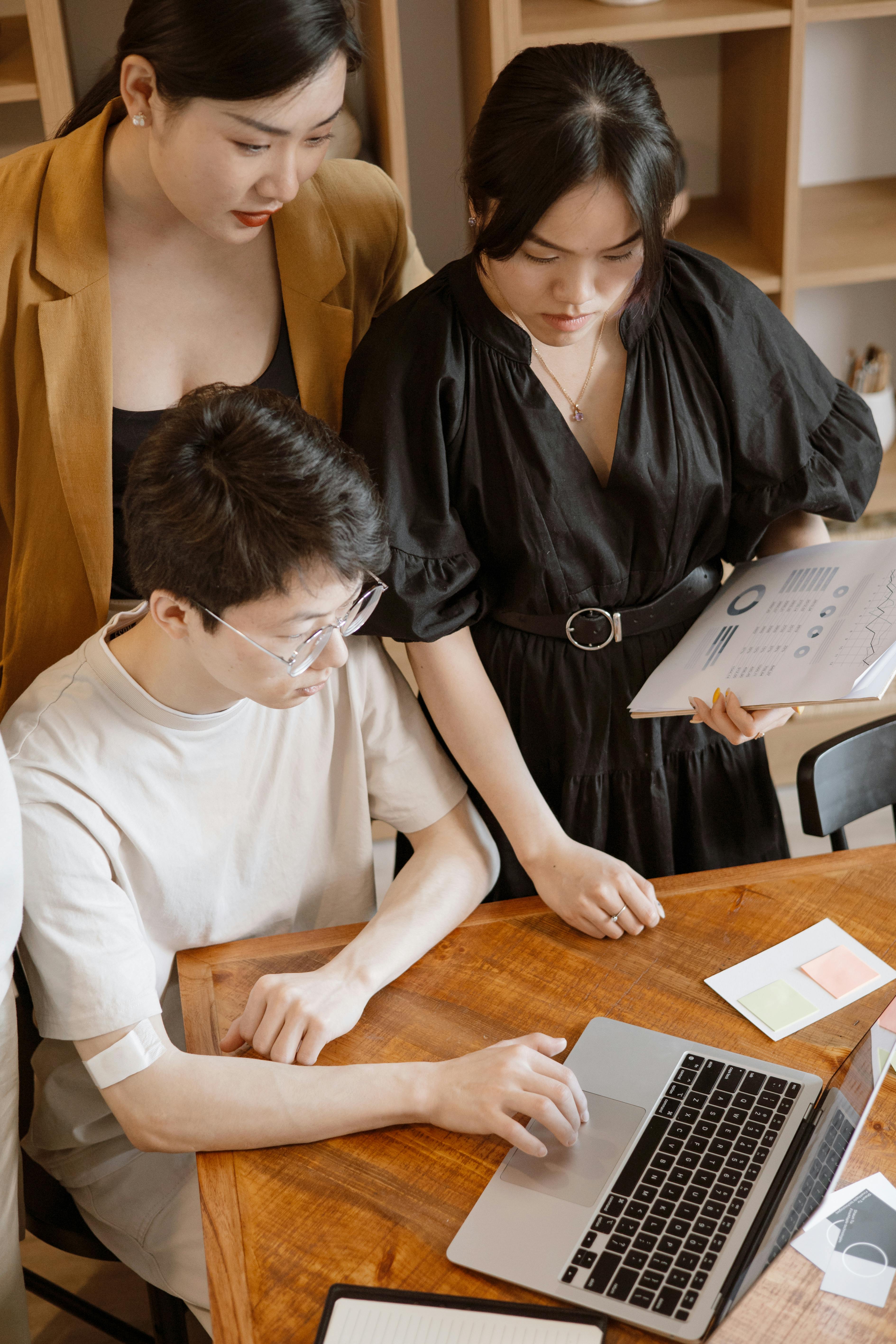 A team reviewing work together around a laptop in an office